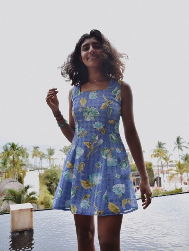 Shania Sandher smiles wearing her favorite thrifted piece - a blue summer dress. 
