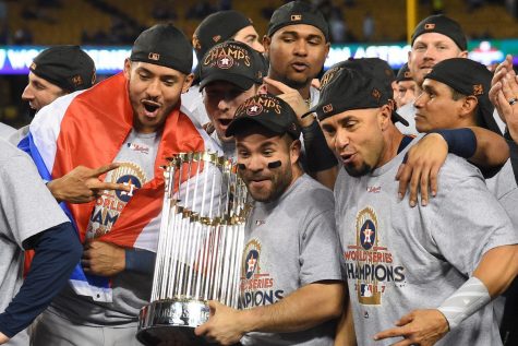 Houston Astros players hoist their trophy high in the air following their 2017 World Series Win. Players celebrate as they have just won their first-ever World Series, it would later come out that they cheated their way to becoming champions.
