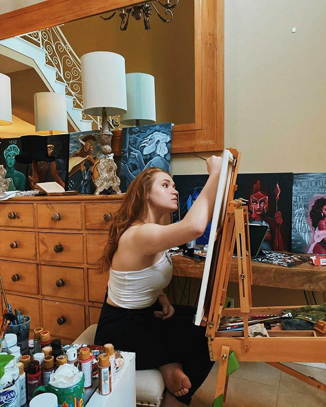 Senior+Natalie+Bennett+poses+among+her+portraits.+Her+paintings+have+reached+millions+of+people+through+the+popular+video-sharing+app%2C+TikTok.