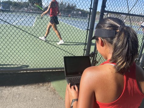 Tennis Player Tara Chelvam is doing her homework during a match. Because she had to leave school early for the match, she didn’t get enough information from class to complete her homework.