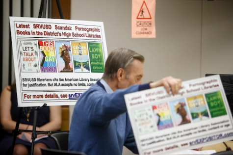 One of the members at the meeting holds up a sign depicting the banned books. He and others spoke about the harmful effects of what they believe to be inappropriate content for children. 