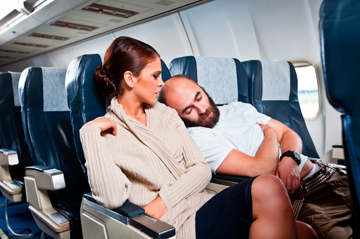 Man rudely sleeping on another passenger. This is a common example of airplane etiquette being violated. 