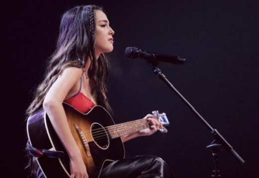 Olivia Rodrigo is playing the guitar and singing live on stage. She was performing at Austin City Limits. 
